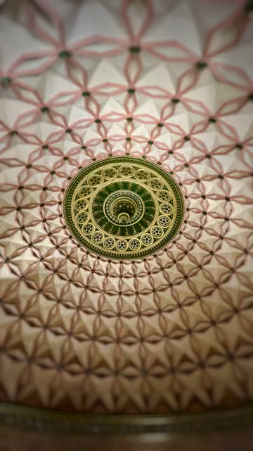 Domed ceiling seen from below, faceted white panels in radiating star pattern with pink ribs and a central gold-and-green medallion