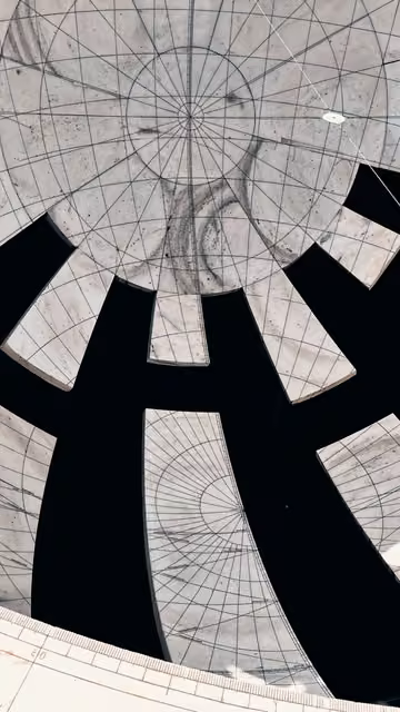 Overhead view of a large stone sundial with radiating marble segments engraved with grid lines, separated by deep black shadow gaps